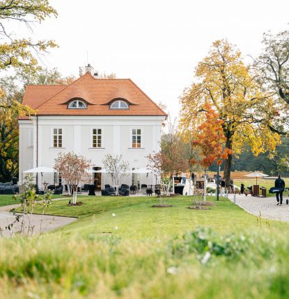 View of two golfers walking towards Nebřenice Chateau at PGA National Czec Republic at Oaks Prague