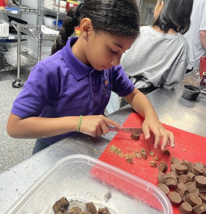 Child at Lyman School chops up Reece's Pieces Cups for the schools fundraiser at Dubsdread Golf Course