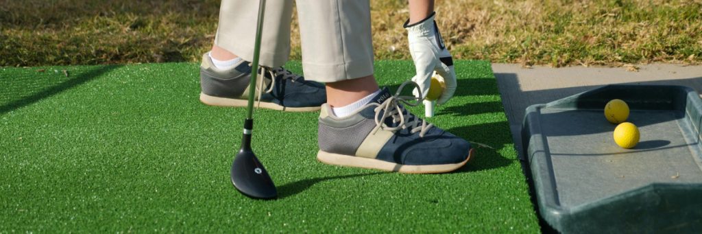 Close-up of teeing up a golf ball on the driving range.